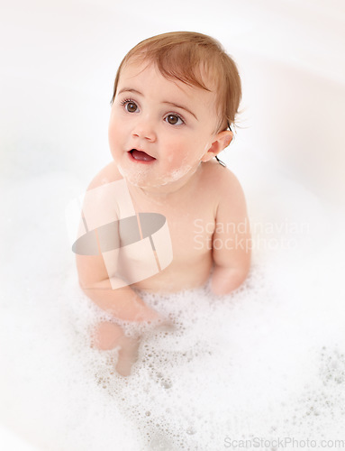 Image of Baby in bathtub with foam, water and clean fun in home for skincare, wellness and hygiene. Bubble bath, soap and happy child in bathroom with cute face, care and washing body of dirt, germs and smile