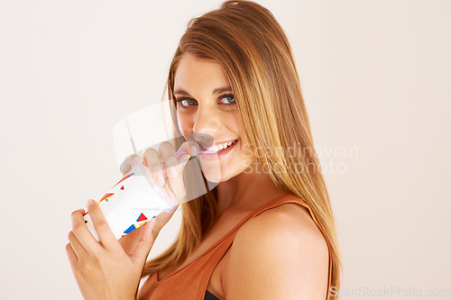 Image of A young woman drinking a soda for happiness, studio and relax wellness on vacation. Model, smile and face with sip straw for fizzy pop, thirsty and sweet seltzer with teenager by white background