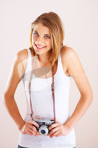 Image of Portrait, smile and shy woman with camera in studio for photography, memory or nature on white background. Face, happy and female photographer with equipment for creative hobby, career or shooting