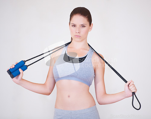 Image of Woman, portrait and skipping rope in studio for exercise cardio or progress training, workout on white background. Female person, face and gym for active lose weight or strong, practice or jumping