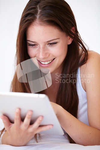 Image of Woman, scroll on tablet and bedroom for online search, social media and sign up to streaming service for film or movies. Happy young person typing on digital technology and relax at home on her bed