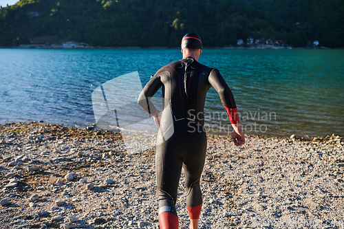 Image of Authentic triathlon athlete getting ready for swimming training on lake