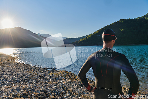 Image of Authentic triathlon athlete getting ready for swimming training on lake