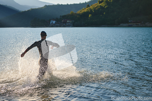 Image of Triathlon athlete starting swimming training on lake