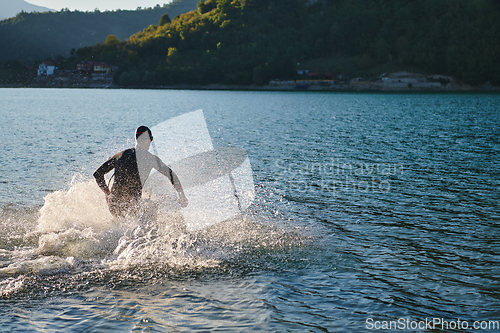 Image of Triathlon athlete starting swimming training on lake