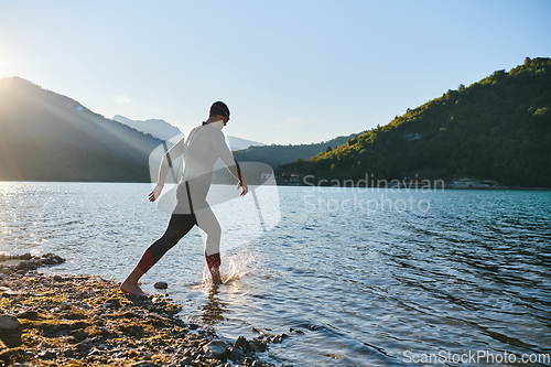 Image of Triathlon athlete starting swimming training on lake