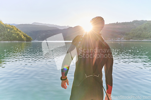 Image of Authentic triathlon athlete getting ready for swimming training on lake