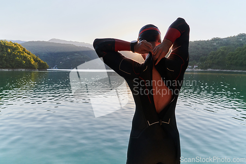 Image of Authentic triathlon athlete getting ready for swimming training on lake