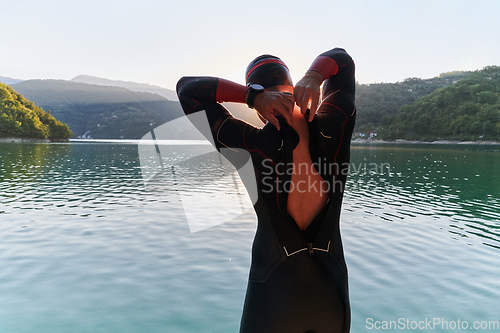 Image of Authentic triathlon athlete getting ready for swimming training on lake