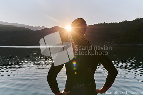 Image of Authentic triathlon athlete getting ready for swimming training on lake