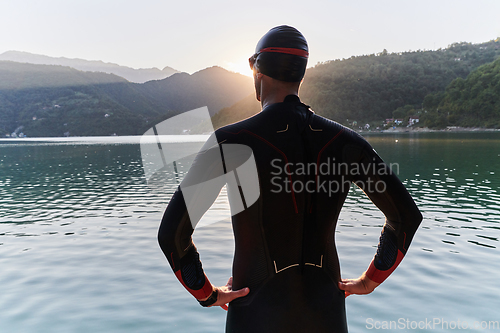 Image of Authentic triathlon athlete getting ready for swimming training on lake