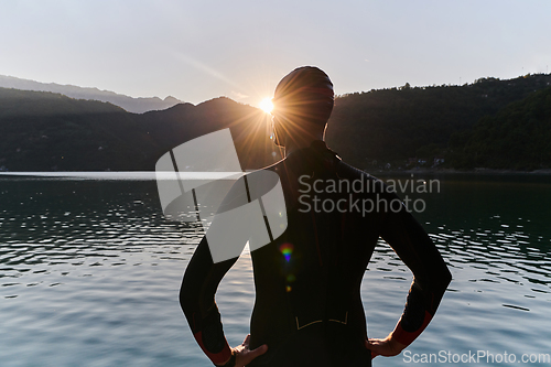 Image of Authentic triathlon athlete getting ready for swimming training on lake