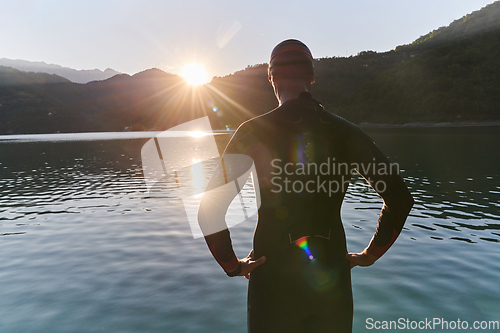 Image of Authentic triathlon athlete getting ready for swimming training on lake