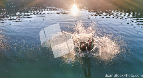 Image of Triathlon athlete swimming on lake in sunrise wearing wetsuit