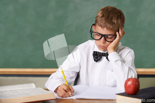 Image of Frustrated boy child, classroom and writing in books for knowledge, information and studying at academy. Student kid, learning and education with glasses, thinking and stress with dyslexia at school