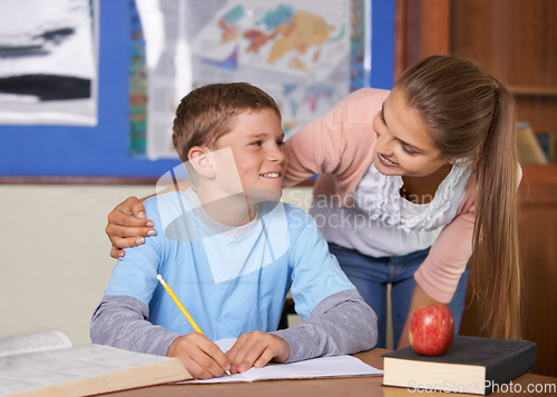 Image of Happy student, teacher and care in support for education, learning or tutor in classroom at school. Woman, mentor or teaching boy or teen in writing, literature or test for exam or help on class desk