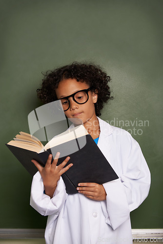 Image of Child, classroom and reading book for education, science learning and physics knowledge on a chalkboard background. Kid or young student with glasses for library resources, textbook and school