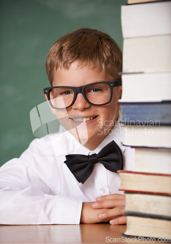 Image of Boy kid, smile and portrait with books, classroom and learning for exam, assessment and studying for knowledge. Student child, notebook and happy for education, development and glasses by chalkboard