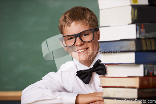 Image of Boy student, smile and portrait with books, classroom and learning for exam, assessment and studying for knowledge. Child, notebook and happy for education, development and glasses by chalkboard