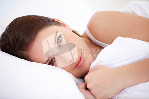 Image of Portrait, home and bedroom with woman, relax and resting with weekend break, lazy and wellness. Face, person and apartment with girl, pillow and peace with freedom, cushion and blanket with health