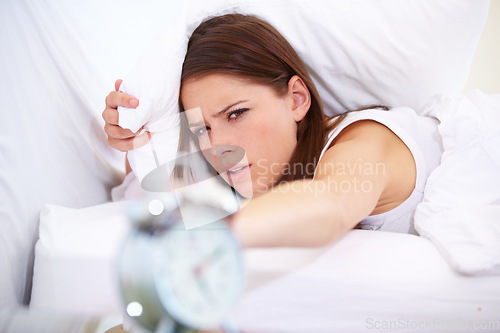 Image of Alarm, clock and angry woman in a bed frustrated with sound, alert or wake up noise at home. Time, stop and face of annoyed female person in bedroom with insomnia, crisis or snooze disaster in house