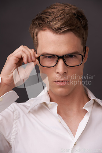 Image of Serious, man and confident portrait with glasses, fashion or choice in eyewear on dark background of studio. Check, optometry and geek with spectacles, style and person with prescription lenses