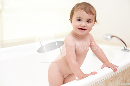 Image of Baby standing in bathtub with smile, water and clean fun in home for skincare, wellness or hygiene. Bubble bath, soap and happy child in bathroom with cute face, care and washing dirt, germs and foam