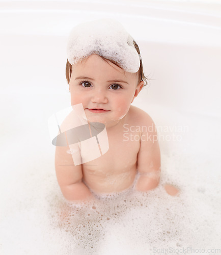 Image of Baby in bath with soap, water and portrait of clean fun in for skincare, wellness and hygiene. Bubbles in bathtub, foam and child in bathroom with cute face, care and washing dirt, germs and smile.