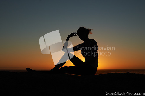 Image of Sunset, silhouette and woman at a beach relax, resting and enjoying quiet morning on sky background. Sunrise, shadow and female person at the ocean for travel, freedom and peaceful me time in nature