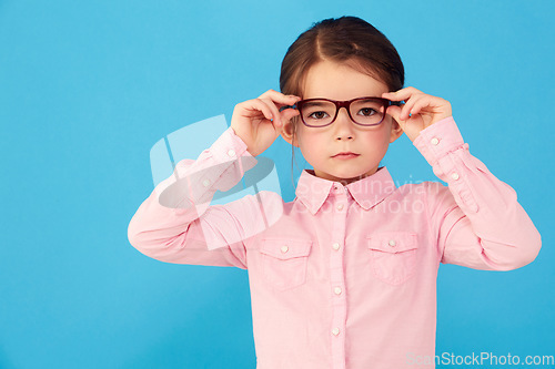 Image of Glasses, child and portrait with eye, geek and modern fashion in a studio with serious face. Kid, eyewear and sight with youth outfit and nerd with accessory and blue background with confidence