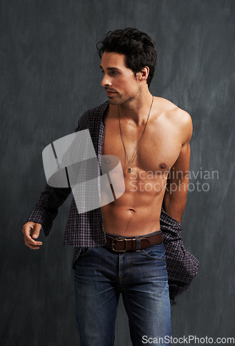 Image of Handsome, fashion and young man by a wall with trendy, cool and stylish outfit with confidence. Abs, attractive and male model from Canada with casual shirt and jeans posing by gray background.