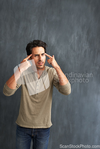 Image of Annoyed, thinking and portrait of man by a wall with doubt, moody and angry facial expression. Upset, question and young male person from Canada with confused face pointing to head by gray background