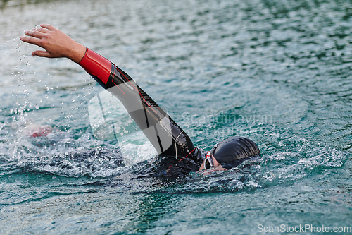 Image of A professional triathlete trains with unwavering dedication for an upcoming competition at a lake, emanating a sense of athleticism and profound commitment to excellence.