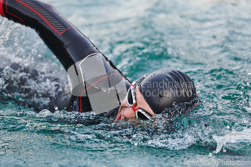 Image of A professional triathlete trains with unwavering dedication for an upcoming competition at a lake, emanating a sense of athleticism and profound commitment to excellence.