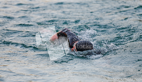 Image of A professional triathlete trains with unwavering dedication for an upcoming competition at a lake, emanating a sense of athleticism and profound commitment to excellence.