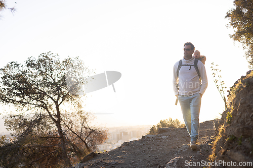 Image of Young father carrying his infant baby boy son in backpack while tracking around Malaga, Spain in sunset. Family travel and vacation concept