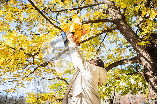 Image of More, more,...dad, that's fun. Happy young father throws his cute little happy baby boy up in the air. Father's Day, Father and his son baby boy playing and hugging outdoors in nature in fall.