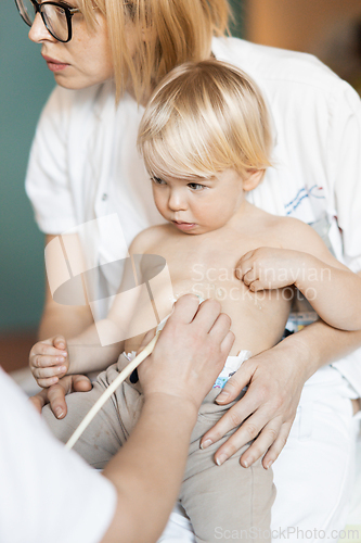 Image of Small child being checked for heart murmur by heart ultrasound exam by cardiologist as part of regular medical checkout at pediatrician.