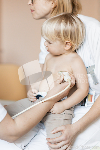 Image of Small child being checked for heart murmur by heart ultrasound exam by cardiologist as part of regular medical checkout at pediatrician.