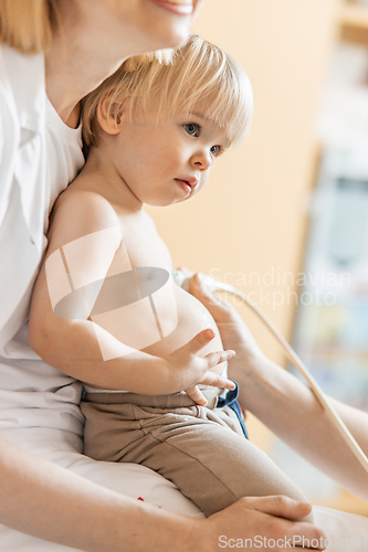 Image of Small child being checked for heart murmur by heart ultrasound exam by cardiologist as part of regular medical checkout at pediatrician.