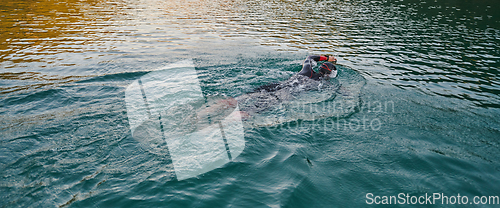 Image of A professional triathlete trains with unwavering dedication for an upcoming competition at a lake, emanating a sense of athleticism and profound commitment to excellence.