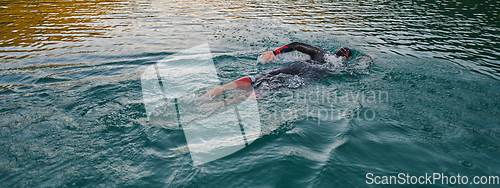 Image of A professional triathlete trains with unwavering dedication for an upcoming competition at a lake, emanating a sense of athleticism and profound commitment to excellence.