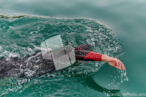 Image of A professional triathlete trains with unwavering dedication for an upcoming competition at a lake, emanating a sense of athleticism and profound commitment to excellence.