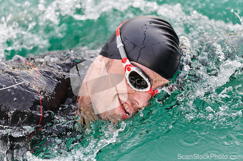 Image of A professional triathlete trains with unwavering dedication for an upcoming competition at a lake, emanating a sense of athleticism and profound commitment to excellence.