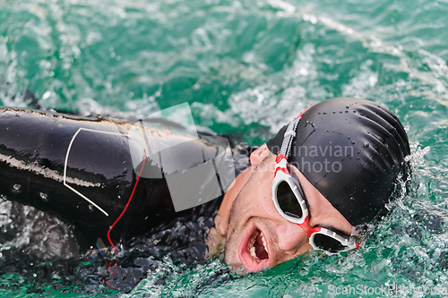 Image of A professional triathlete trains with unwavering dedication for an upcoming competition at a lake, emanating a sense of athleticism and profound commitment to excellence.