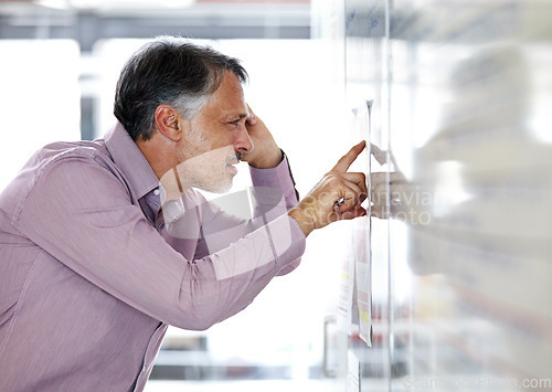 Image of Senior businessman, pointing and thinking on whiteboard in brainstorming or planning at office. Mature man in wonder, thought or decision for idea, problem solving or solution for agenda at workplace