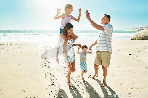 Image of Parents, children and beach for high five happy or summer travel vacation, ocean sunshine or family development. Man, woman and kids on sand for holiday relax walking or outdoor, clean air or smile