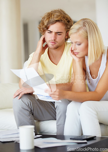 Image of Couple, confused for bills and reading documents on sofa with debt, financial planning or budget risk and stress at home. Serious man and woman thinking of loan, house expenses or mortgage paperwork