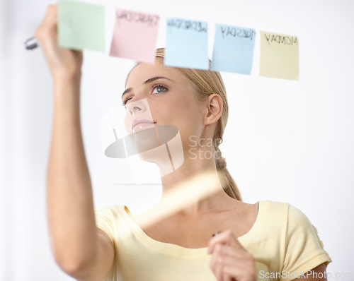 Image of Business woman, writing and schedule planning on sticky notes or glass board for project or time management. Creative planner or worker with priority list, calendar or brainstorming of workflow ideas