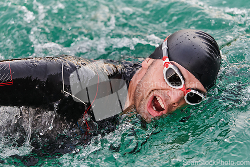 Image of A professional triathlete trains with unwavering dedication for an upcoming competition at a lake, emanating a sense of athleticism and profound commitment to excellence.